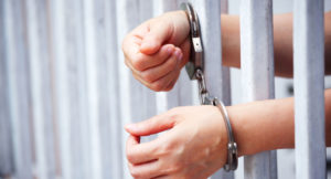 Woman in Jail behind bars handcuffed